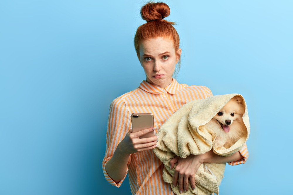 Puzzled woman looking at mobile phone, unsure of veterinary contact number