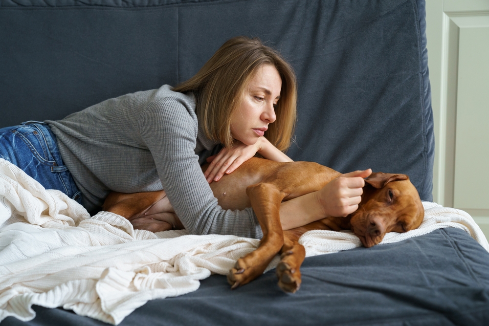 Worried woman caring for a weakening senior dog at home, highlighting geriatric pet care